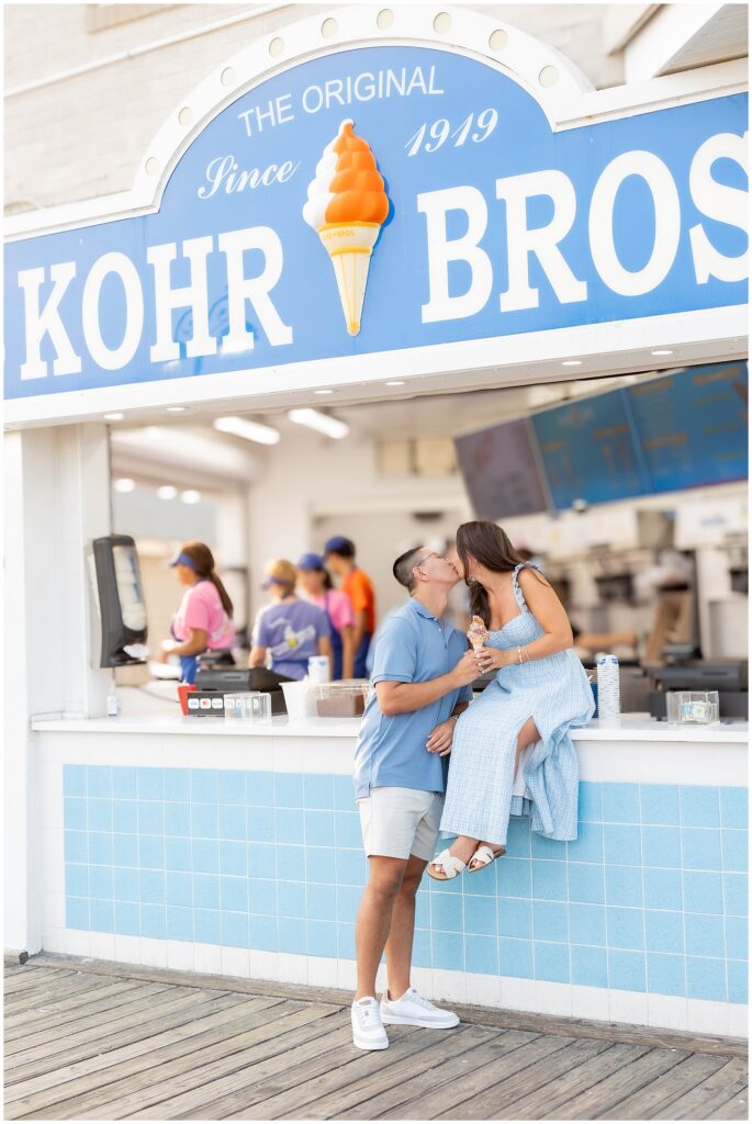 Ocean City NJ engagement couple walking along the colorful boardwalk